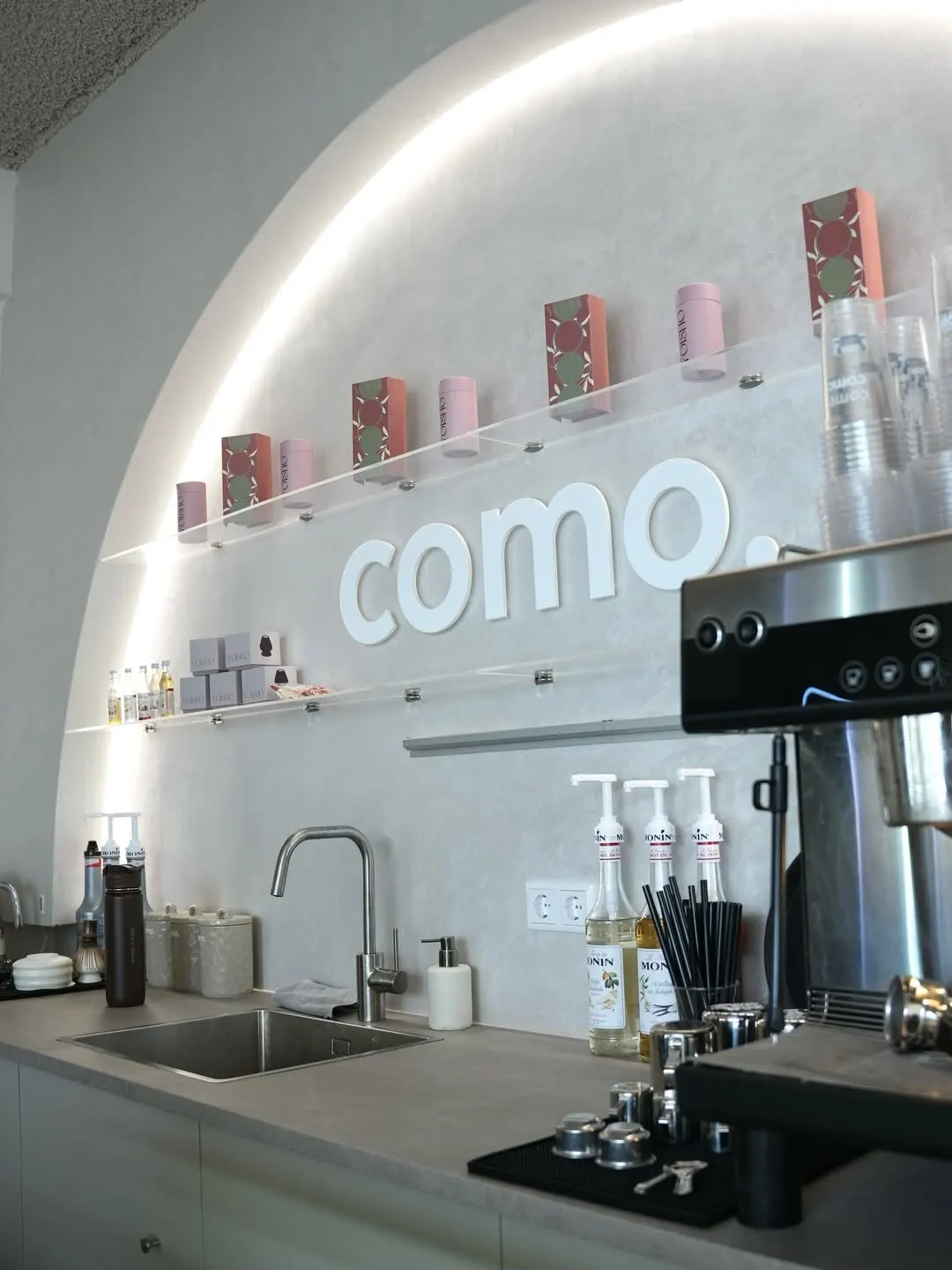 De verlichte boog achter de bar van COMO met het logo aan de wand