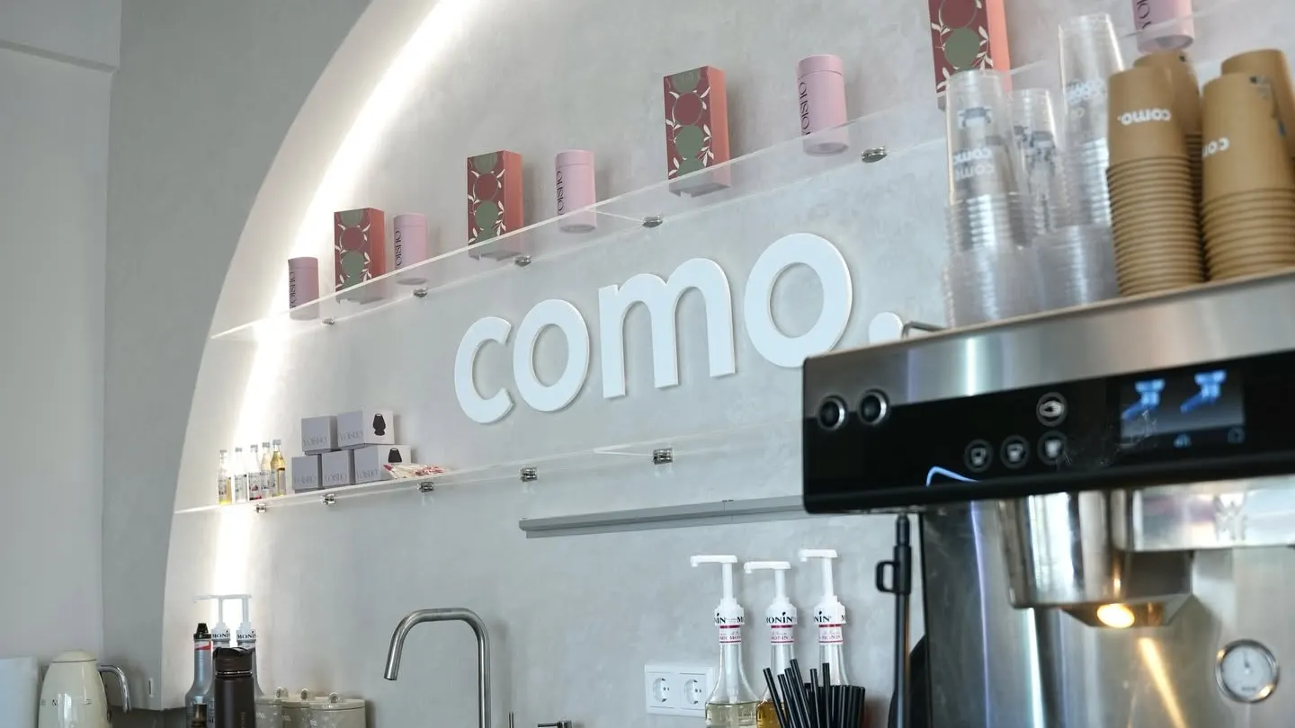 De bar van COMO met de verlichte boog en het logo aan de wand