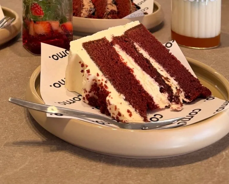 Een punt red velvet met roomlaagjes op een COMO-bordje