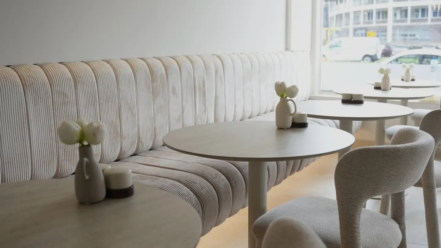 De zaal van COMO met de lange geribde bank en ronde tafels