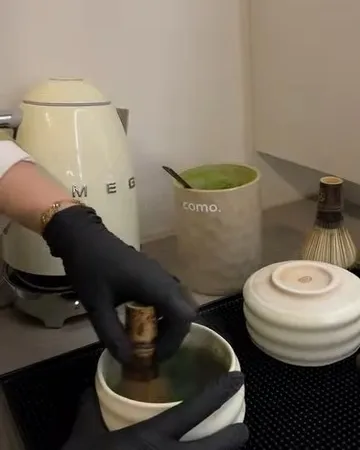 Matcha wordt met een bamboe garde geklopt in een kom achter de bar