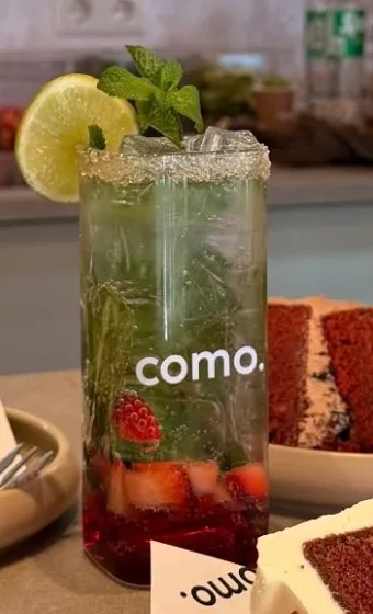 Een mocktail met munt, limoen en aardbeien in een gemerkt COMO-glas
